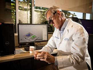 A male faculty member in the College of Dentistry examining a model of teeth.